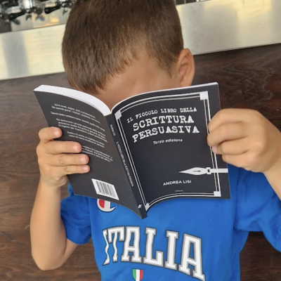 bimbo che tiene in mano piccolo libro della scrittura persuasiva